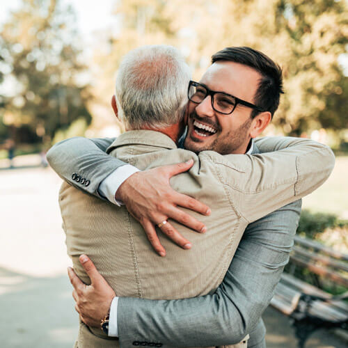 A younger man hugging an older man outdoors.