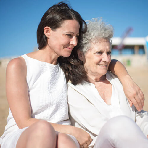 Two women sitting on the beach, enjoying the view and each other's company.