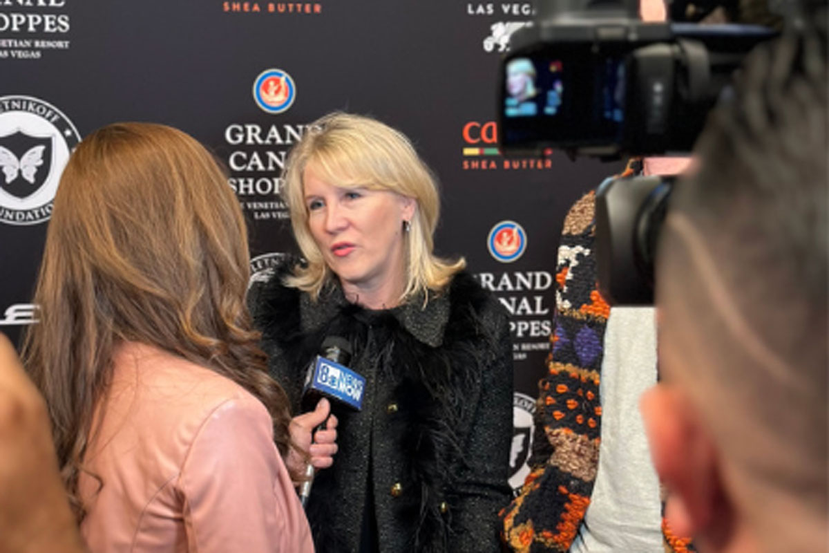 A woman being interviewed on a red carpet speaks into a microphone while cameras record the moment.
