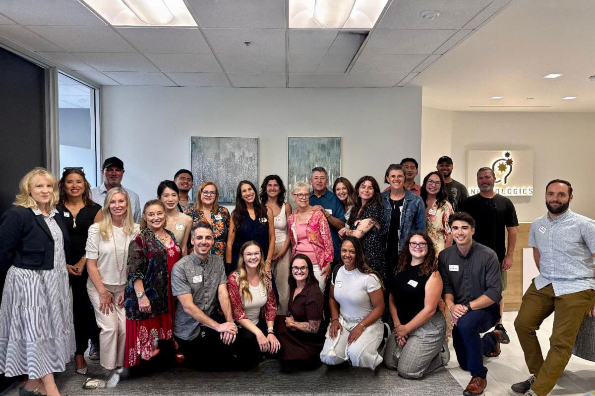 july_newsletter_2026_3 A large group of smiling attendees posing together for a group photograph in the reception area of a Neurologics office.